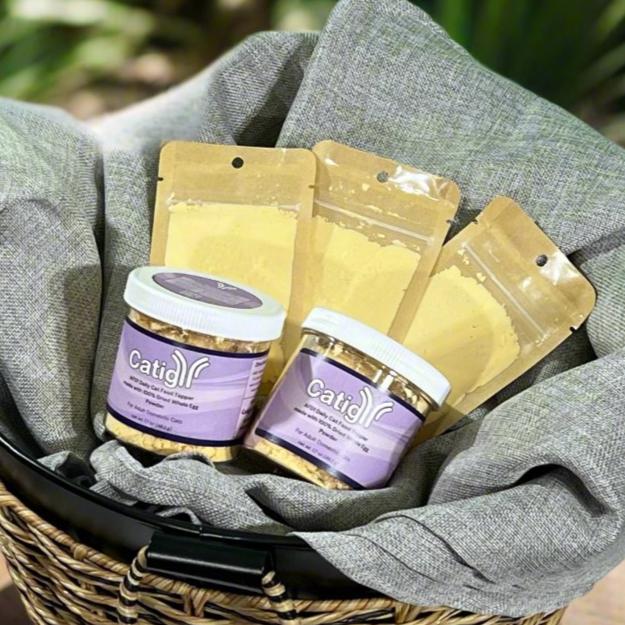 jarred catigy egg powder and resealable sample bag of fel d 1 allergen reducing egg powder in a rustic basket in a back yard